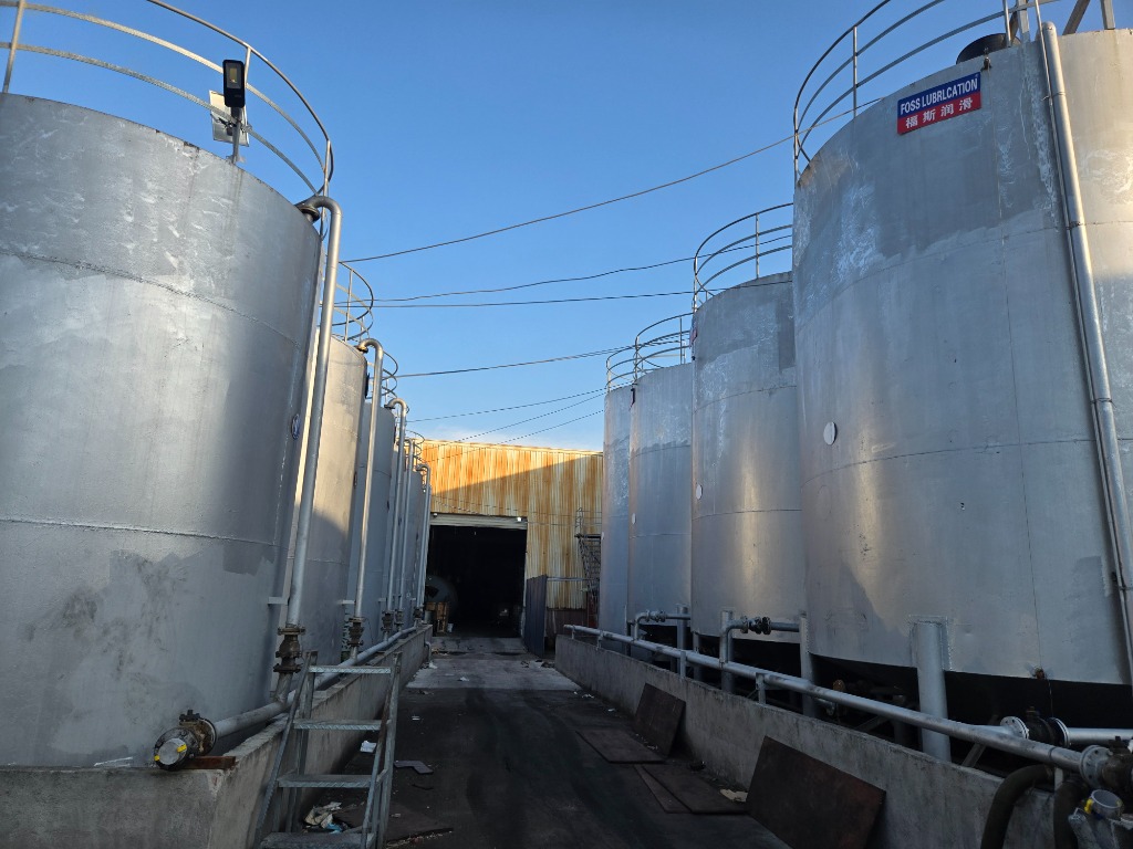 Central corridor flanked by dual rows of outdoor base oil storage tanks leading into the blending plant